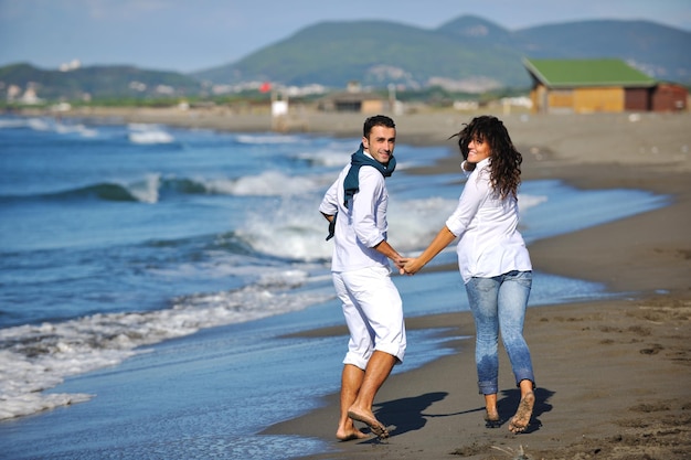 casal jovem feliz em roupas brancas tem recreação romântica e diversão na bela praia de férias