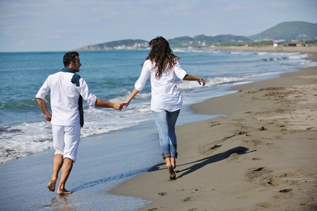 casal jovem feliz em roupas brancas tem recreação romântica e diversão na bela praia de férias