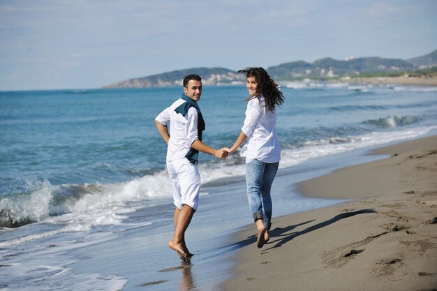 casal jovem feliz em roupas brancas tem recreação romântica e diversão na bela praia de férias