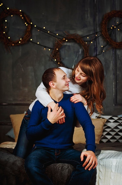 casal jovem feliz, família. Mulher bonita, homem bonito relaxando no quarto moderno na cama, beijando