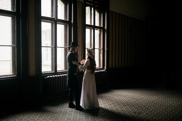 Casal jovem feliz Noivas de chapéu Moça em um vestido de noiva branco e chapéu com um buquê de flores Noivas no castelo Noiva e noivo