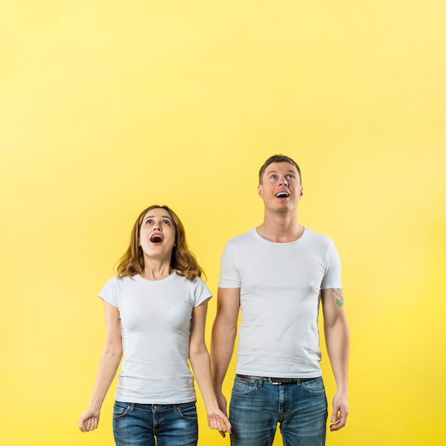 Casal jovem feliz olhando contra fundo amarelo