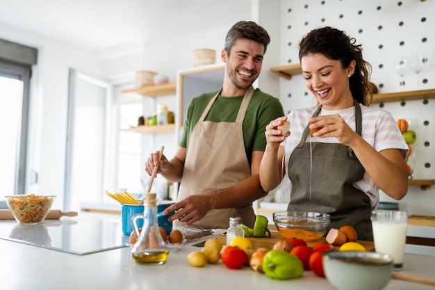 Casal jovem feliz preparando comida na cozinha em casa. Comida saudável, conceito de pessoas