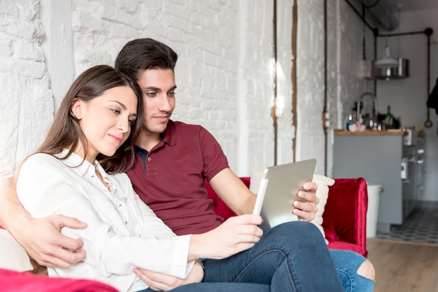 Casal jovem feliz relaxado em casa com um tabet