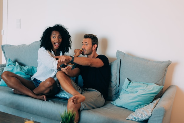 Casal jovem feliz relaxado em casa no sofá se divertindo assistindo tv