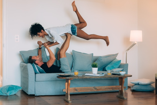 Casal jovem feliz relaxado em casa no sofá se divertindo brincando uns com os outros