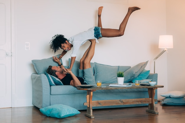 Foto casal jovem feliz relaxado em casa no sofá se divertindo brincando uns com os outros