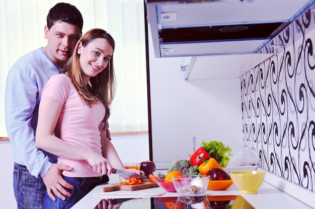 casal jovem feliz se diverte enquanto prepara comida fresca saudável na cozinha