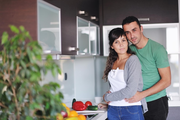 casal jovem feliz se diverte na cozinha moderna interior enquanto prepara frutas frescas e salada de legumes