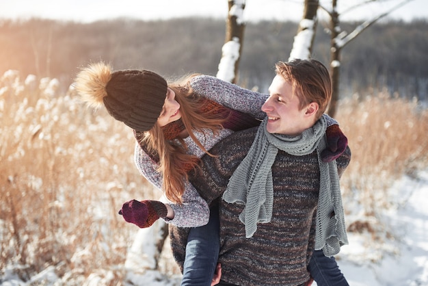 Casal jovem feliz se diverte na neve fresca no dia ensolarado de inverno bonito de férias