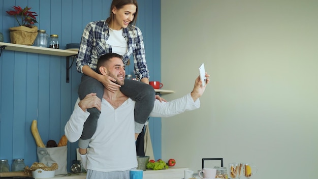 Casal jovem feliz se divertindo e conversando com videochamada online na cozinha em casa