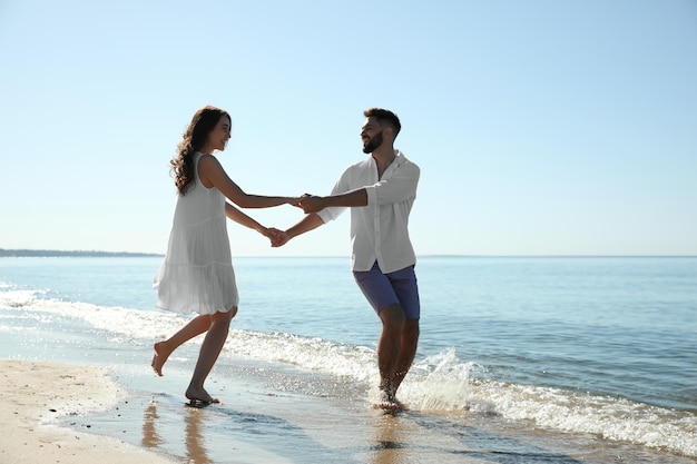Casal jovem feliz se divertindo na praia perto do mar Viagem de lua de mel