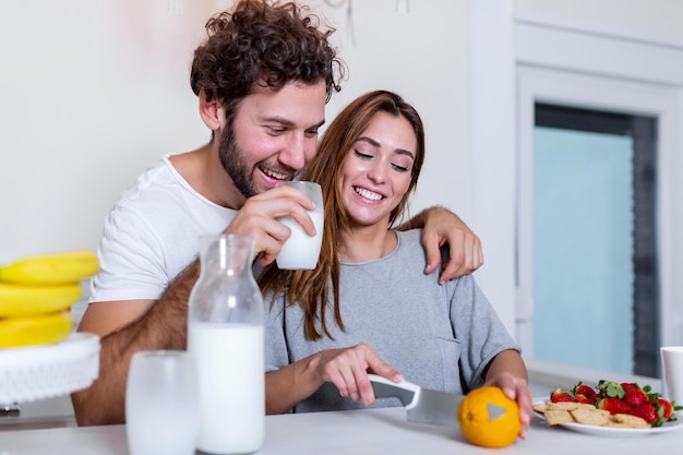 Casal jovem feliz se divertir na cozinha moderna interna, enquanto prepara a salada de alimentos de frutas e vegetais frescos. Lindo casal jovem conversando e sorrindo enquanto cozinha uma comida saudável na cozinha em casa.