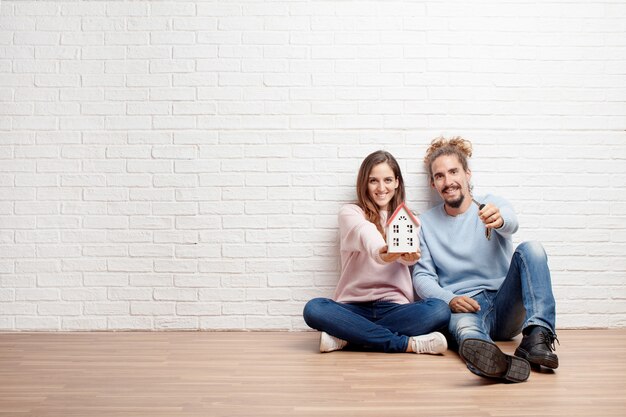 Casal jovem feliz sentada no chão de sua nova casa. conc.