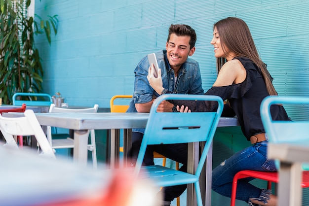 Casal jovem feliz sentado em um restaurante com um smartphone