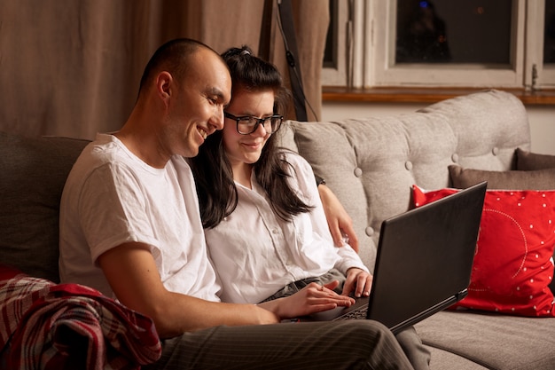 Casal jovem feliz sentados juntos, olhando para um laptop