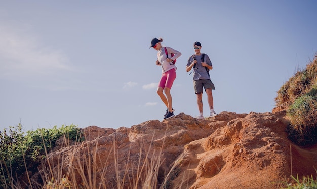 Casal jovem feliz sobe ao topo das montanhas perto do oceano