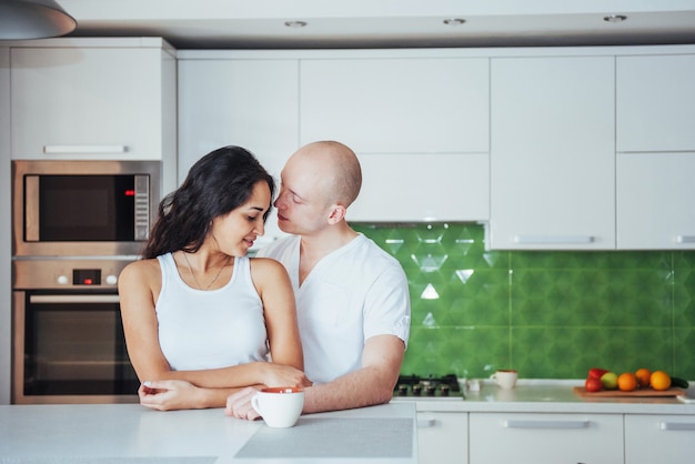 Casal jovem feliz tomando café na cozinha