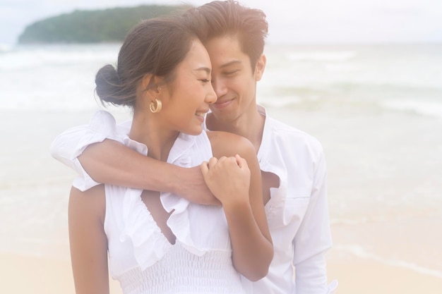 Casal jovem feliz usando vestido branco na praia nos feriados viaja conceito de casamento romântico