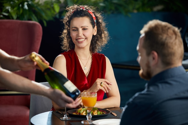 Casal jovem jantando no garçom do restaurante trouxe uma garrafa de champanhe