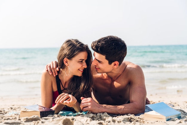 Casal jovem, lendo um livro na praia tropical. Casal relaxante na praia. Férias de verão