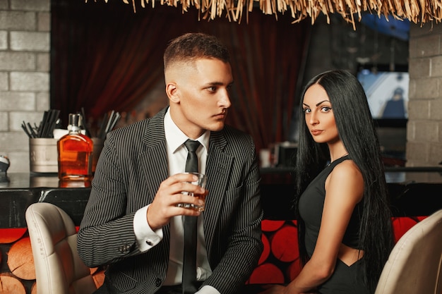 Casal jovem lindo e elegante relaxando em um bar