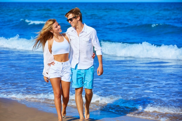 Casal jovem loiro andando na praia