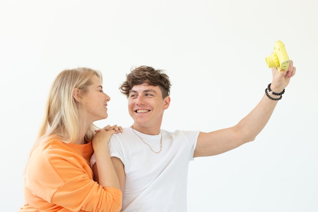 Casal jovem louco engraçado loira e um cara hipster tirando uma selfie em um filme amarelo vintage