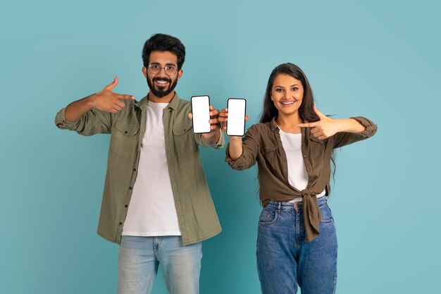 Foto casal jovem multicultural feliz segurando telefones com tela branca