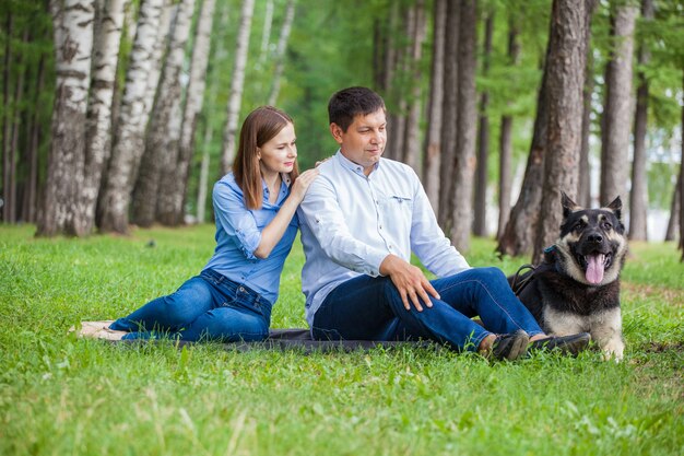 Casal jovem passeando com um cão pastor na floresta