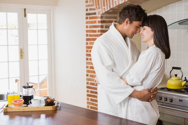 Casal jovem romântico, abraçando um ao outro na cozinha