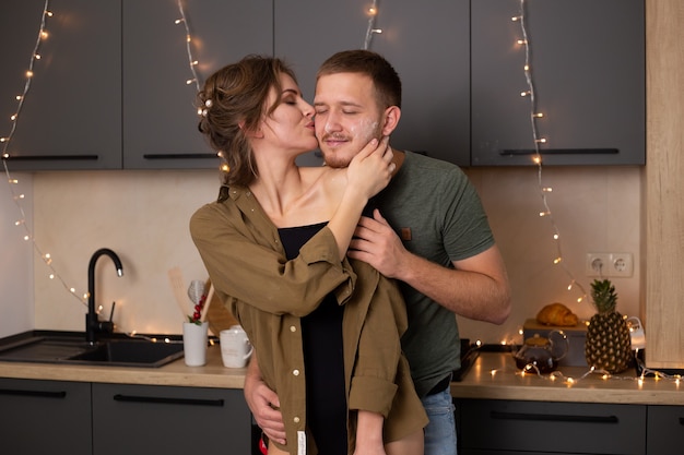 Casal jovem romântico beijando enquanto cozinham juntos na cozinha, se divertindo muito juntos.