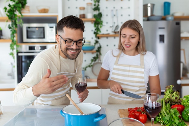 Casal jovem romântico cozinhando juntos na cozinha se divertindo juntos Homem e mulher rindo de manhã com café da manhã