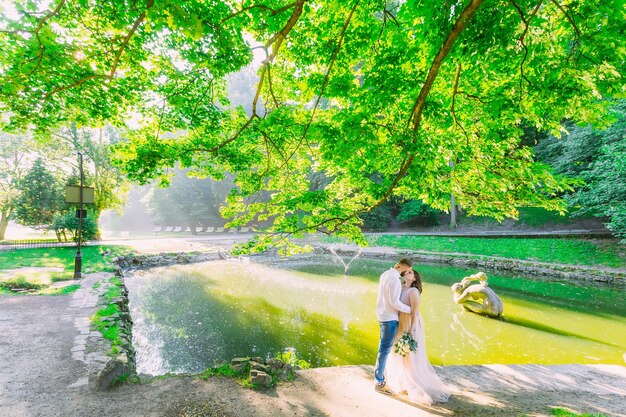 Casal jovem romântico se divertindo no parque da cidade perto da fonte Linda garota de vestido longo