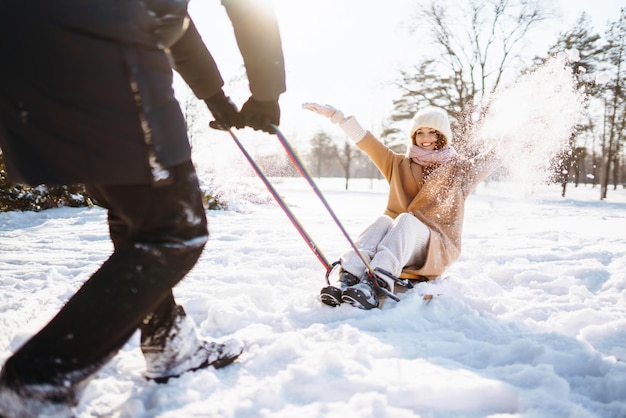 Casal jovem se divertindo e rola em um trenó na floresta de neve de inverno Conceito de férias da natureza