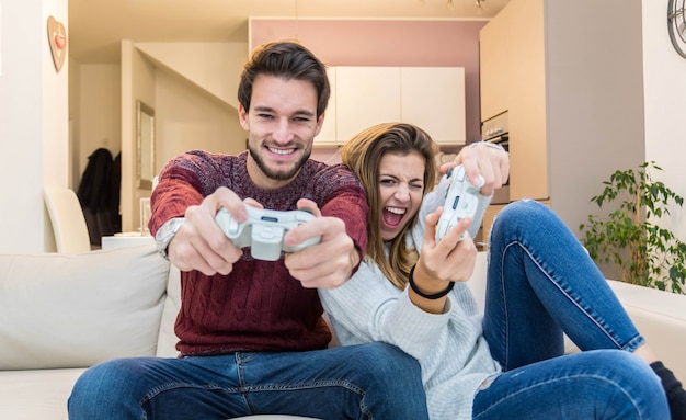 Casal jovem se divertindo jogando videogame em casa.