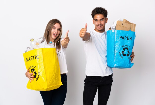 Casal jovem segurando um saco cheio de plástico e papel branco com o polegar para cima porque algo bom aconteceu