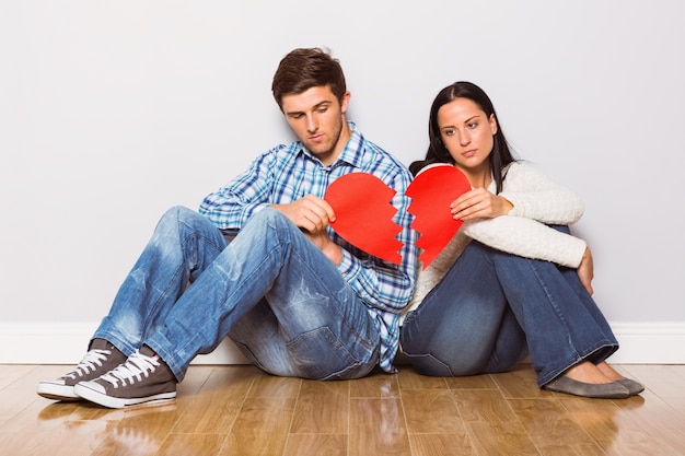 Casal jovem sentado no chão com coração partido