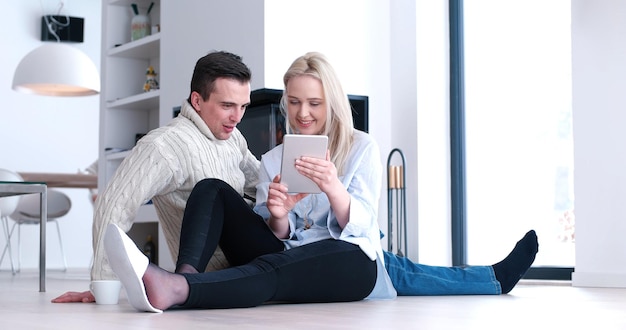 Casal jovem sentado no chão e usando internet em tablet digital