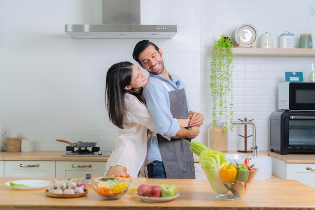 Casal jovem sorridente cozinhando na cozinha Casal jovem birracial alegre e brincalhão amassando massa no balcão da cozinha Casal jovem feliz cozinhando