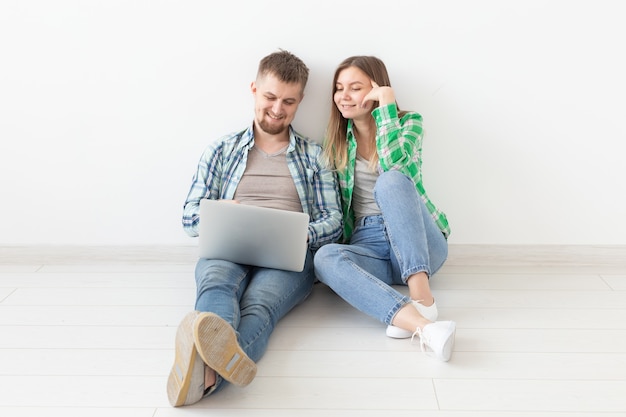 Casal jovem sorridente faz compras online de móveis em seu novo apartamento hipotecário.