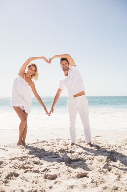 Casal jovem sorridente fazendo formato de coração