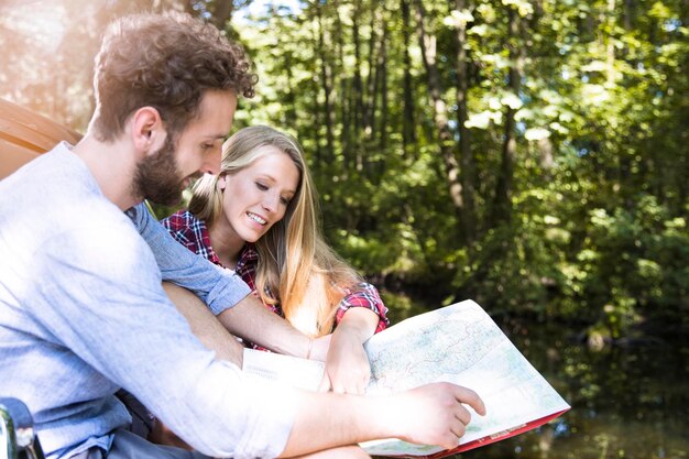 Casal jovem sorridente lendo mapa em um riacho