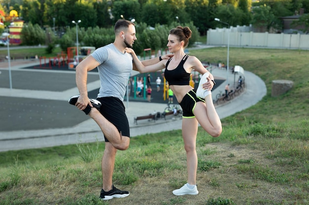 Casal jovem treina ao ar livre em um parque no verão ao pôr do sol