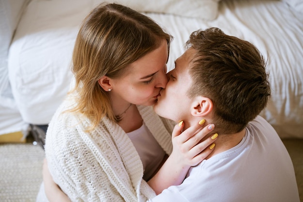 Casal jovem, um cara e uma garota de etnia caucasiana, em camiseta branca, se beijando