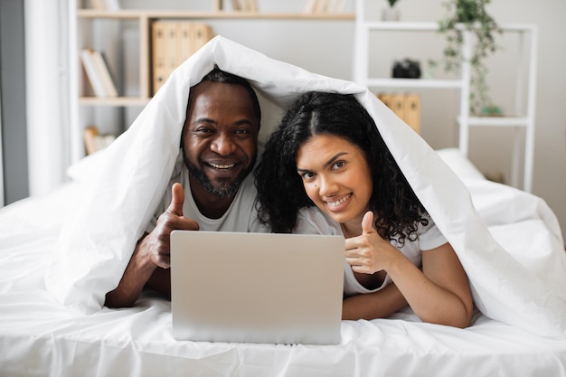 Casal jovem usando laptop enquanto estava deitado na cama