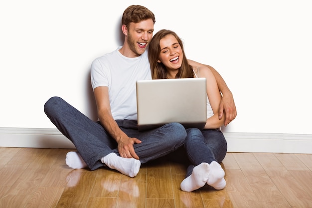Casal jovem usando laptop no chão