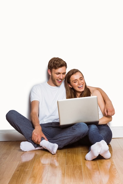 Casal jovem usando laptop no chão