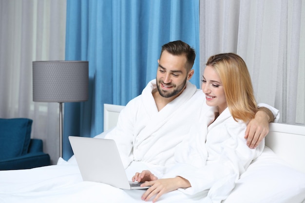 Casal jovem usando laptop no quarto de hotel