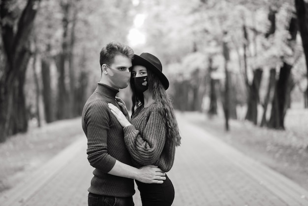 Casal jovem usando máscaras na floresta, parque